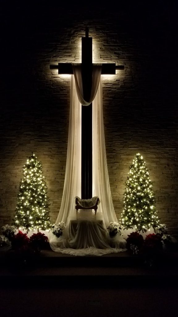 Cross with two christmas trees on the left and risht side.