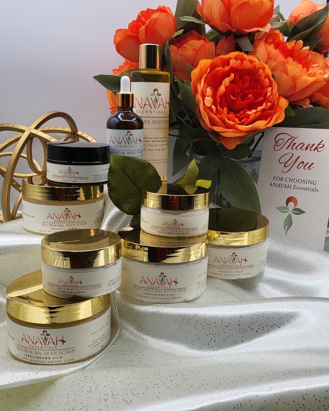 Display of body butter and oil jars with orange flowers to the right of the display. Products sit on a white cloth.
